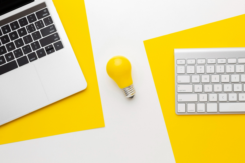 two keyboards are on the desk with a yellow light bulb in the middle. It meant to be symbolize the website maintenance and optimisation service
